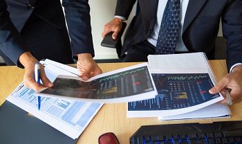 Investor and trader discussing statistic data Investor and trader discussing statistic data, holding papers with financial charts and pen. Cropped shot. Broker job or trading concept
